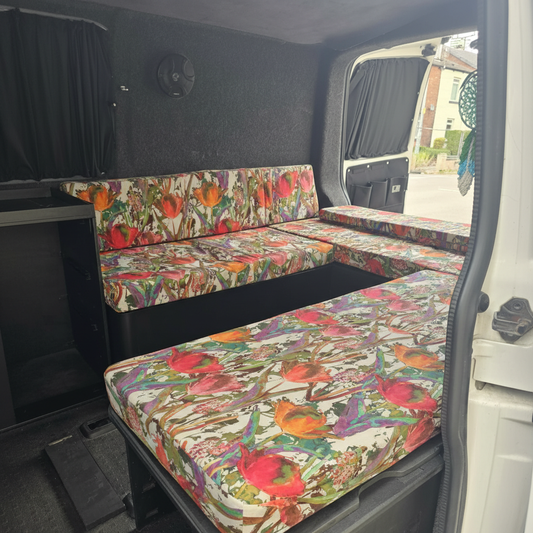 Bright watercolour floral campervan cushions with red and orange tulips on a slide out bed
