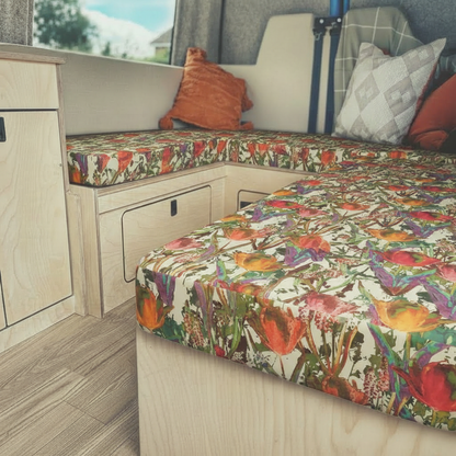 Vibrant floral Campervan seat covers in a conversion van-Custom foam pads with red tulip pattern for motorhomes-DIY van conversion cushions fitted on wooden bench-Close up of patterned Leisure vehicle upholstery fabric-Bright floral interior design for campervan renovation

